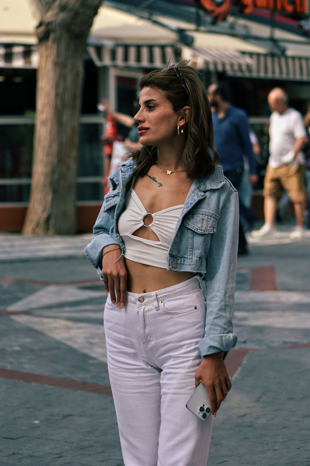 Cropped blue denim jacket, white cutout cropped top and pale lilac high-waisted trousers; lower legs outside the frame.