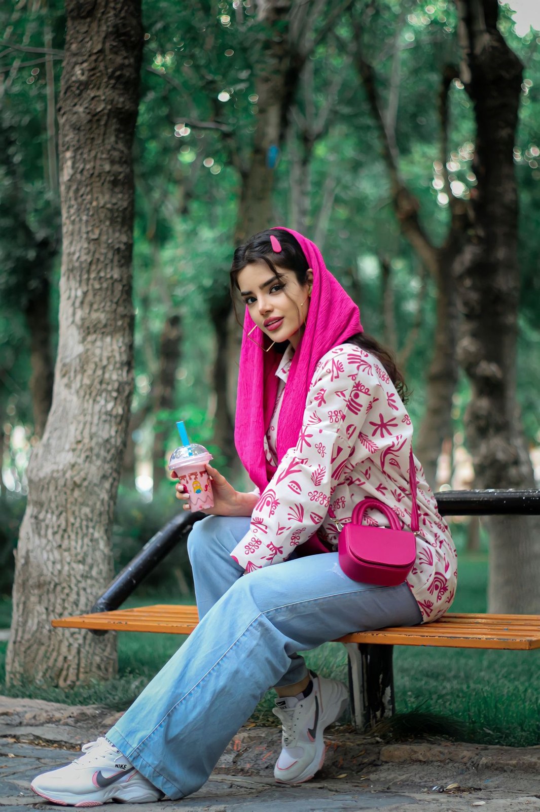 Floral shirt with blue jeans, grey trainers, bright pink headscarf and matching small handbag.