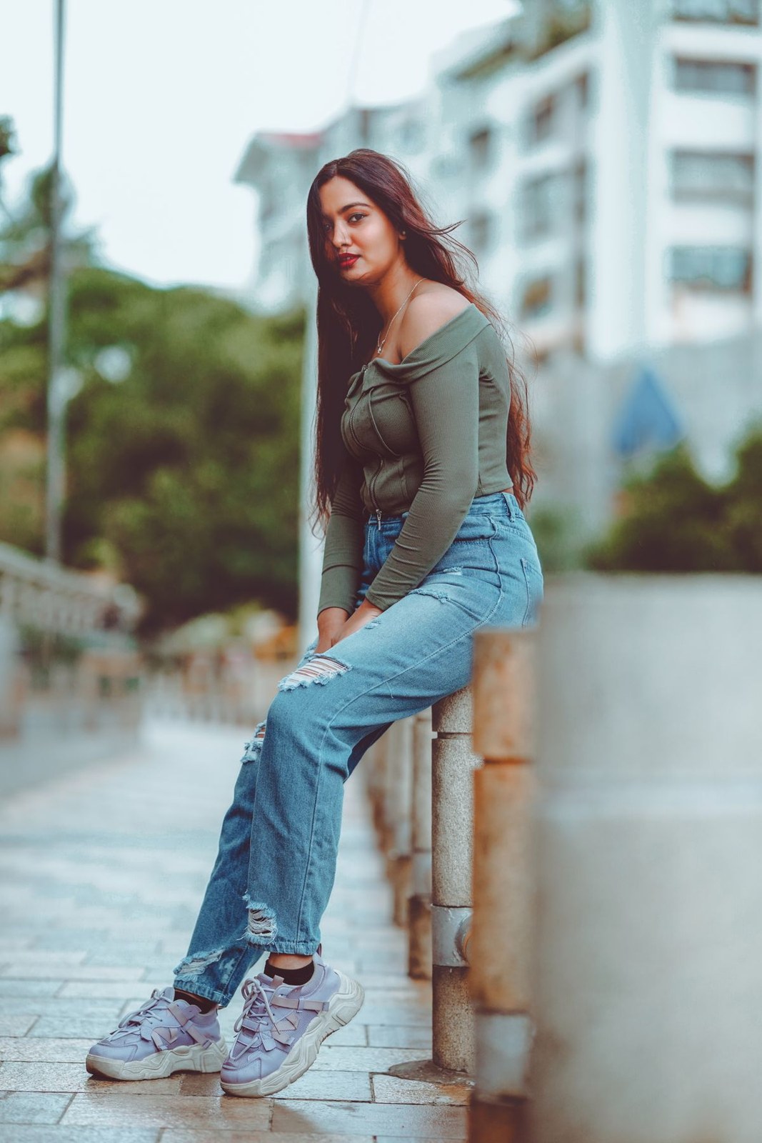 Olive fitted long-sleeve top, flared blue jeans and chunky white trainers.