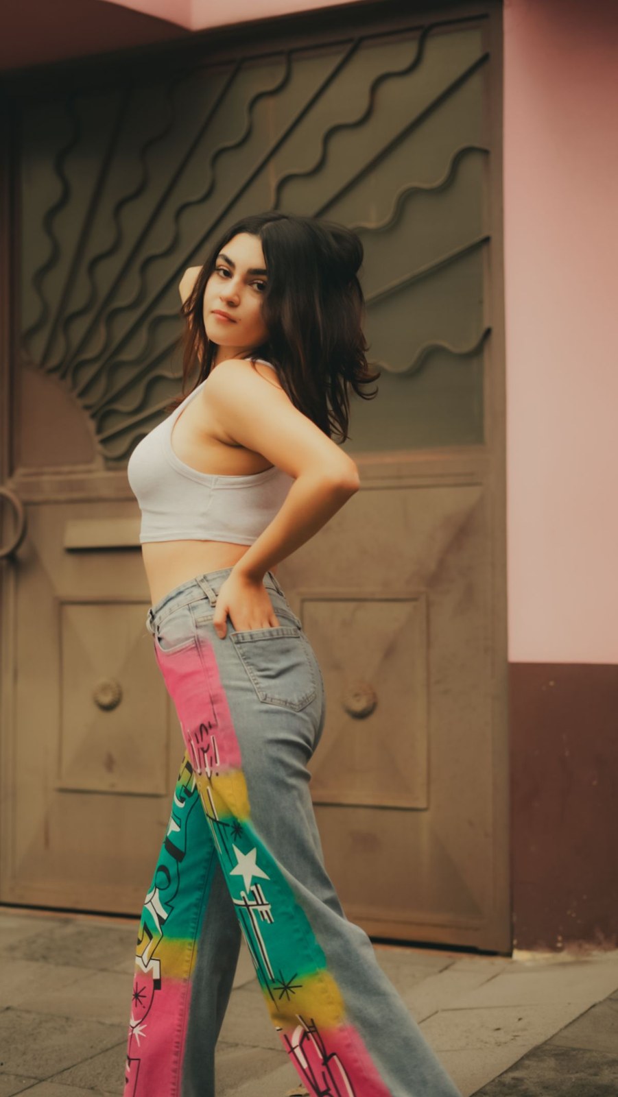 Grey cropped tank, grey jeans and a bright multicolour scarf tied at the hip.