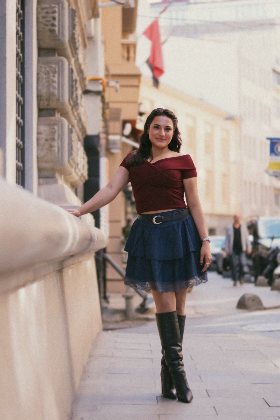Burgundy fitted T-shirt, short blue skirt, black belt and tall black lace-up boots.