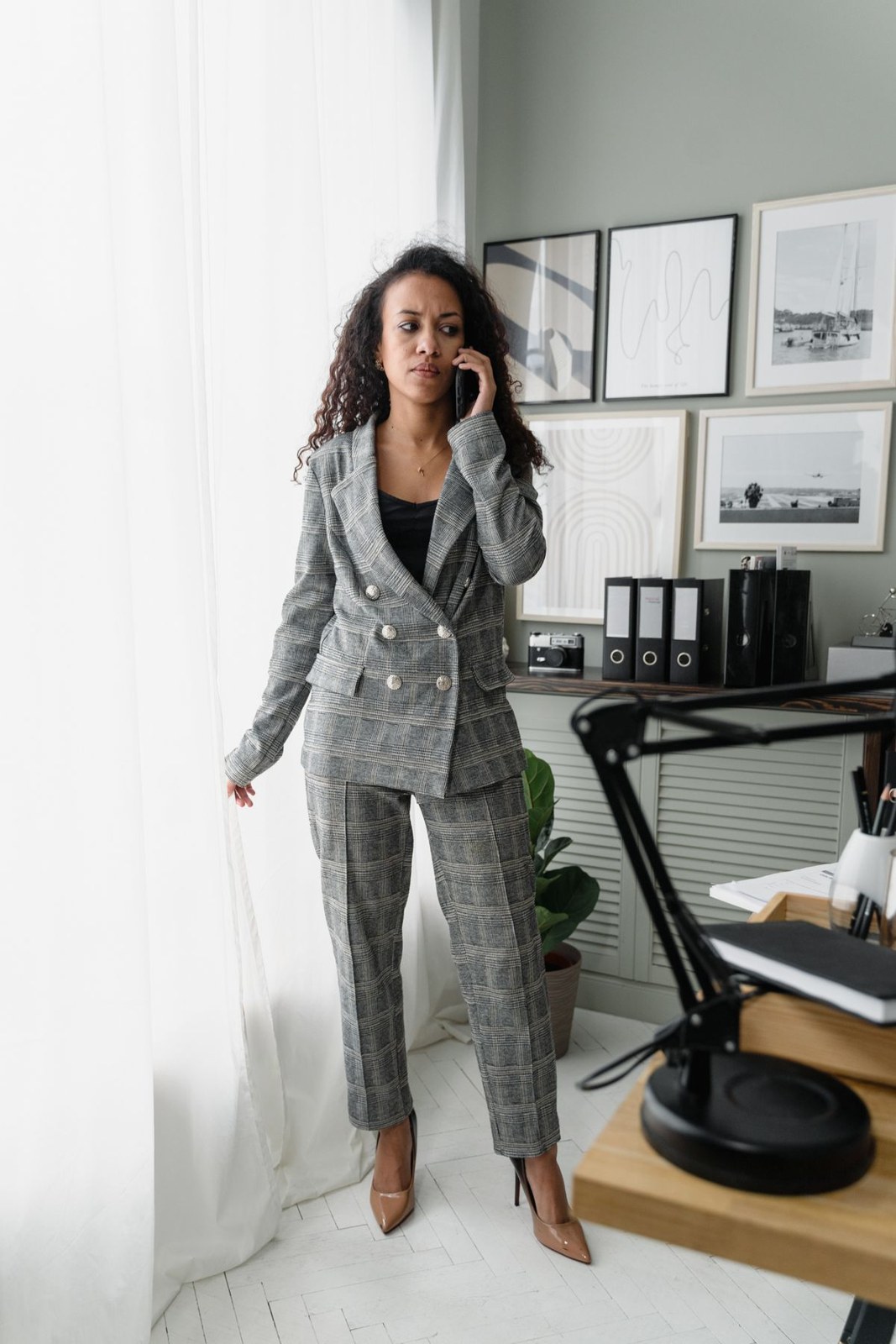 Grey checked double-breasted trouser suit with a dark top and pale pointed heels.