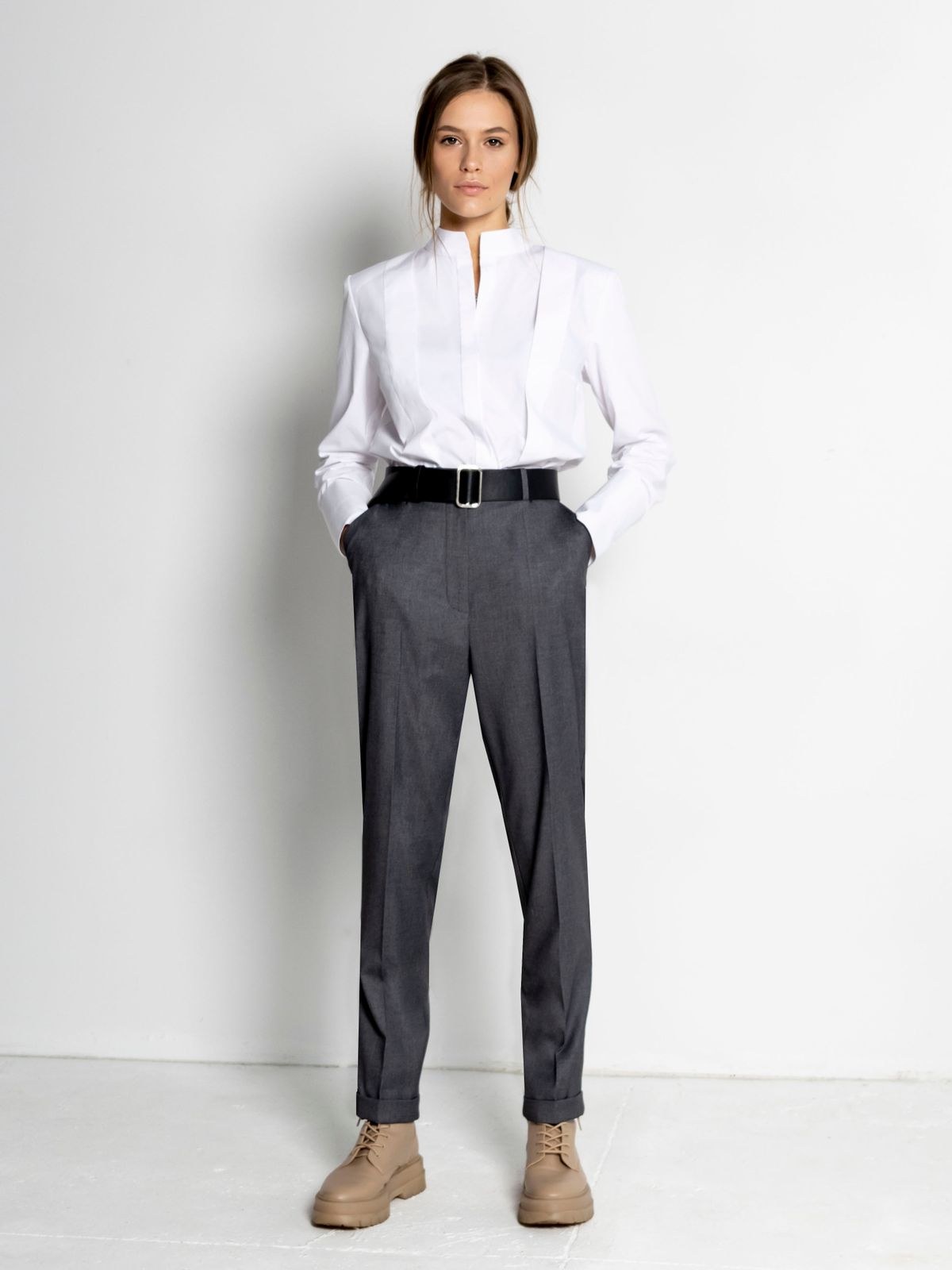 White long-sleeve blouse tucked into high-waisted grey pinstriped trousers, with black belt and tan loafers.