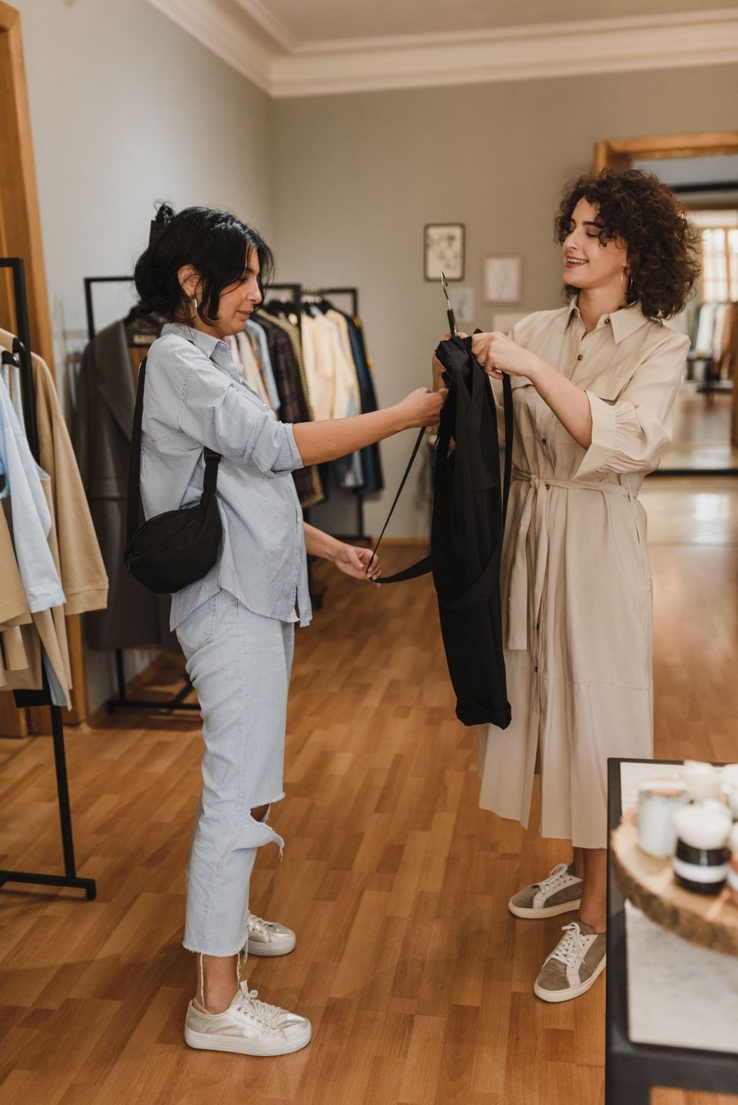 Pale denim shirt and cropped jeans with white trainers and a black shoulder bag, beside a beige belted dress.