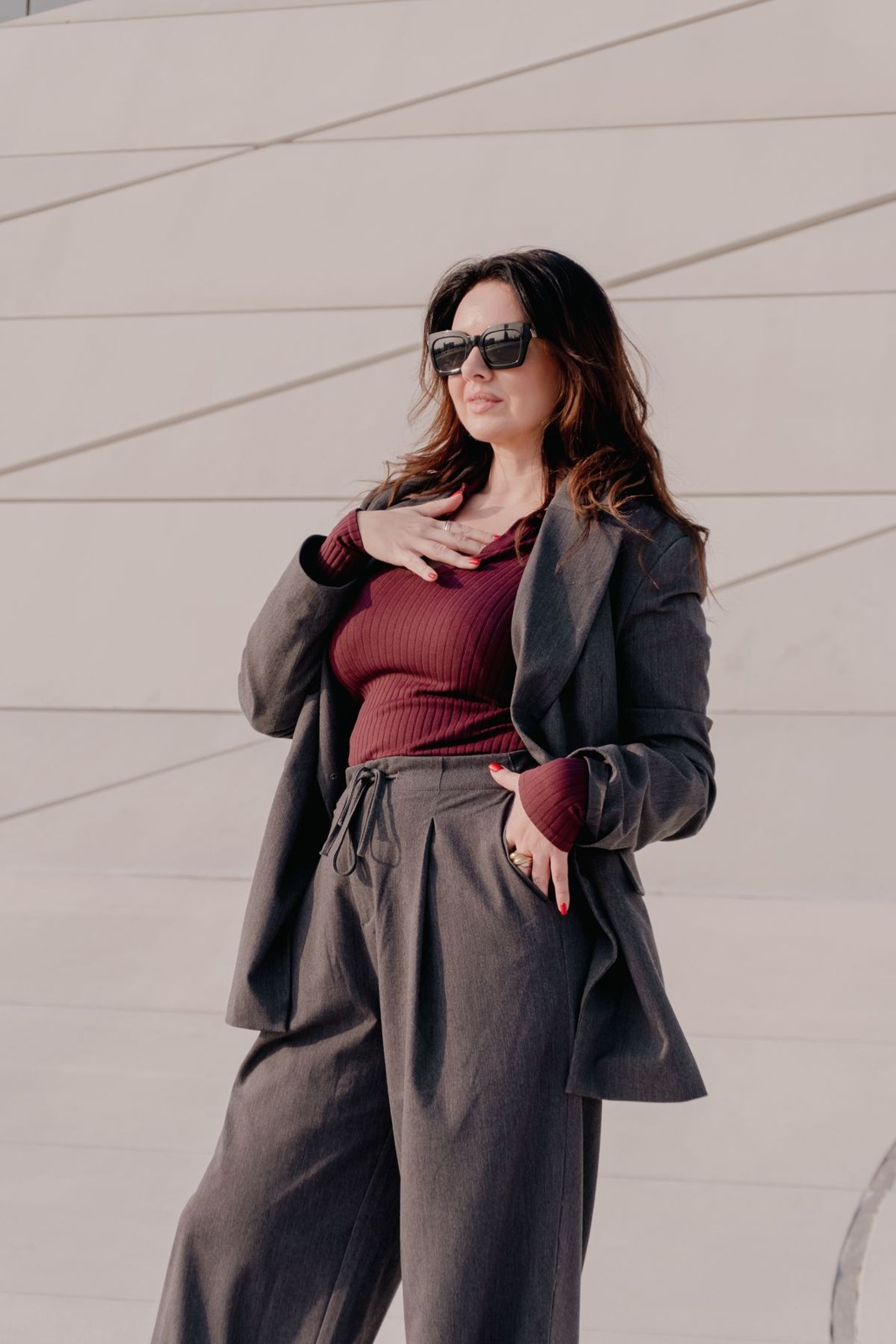 Oversized grey blazer, burgundy top, high-waisted grey trousers and sunglasses.