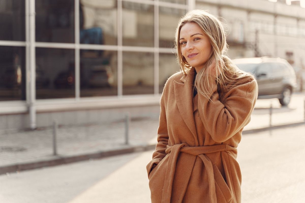 Camel wrap coat tied at the waist, with broad lapels; upper-body outdoor portrait.
