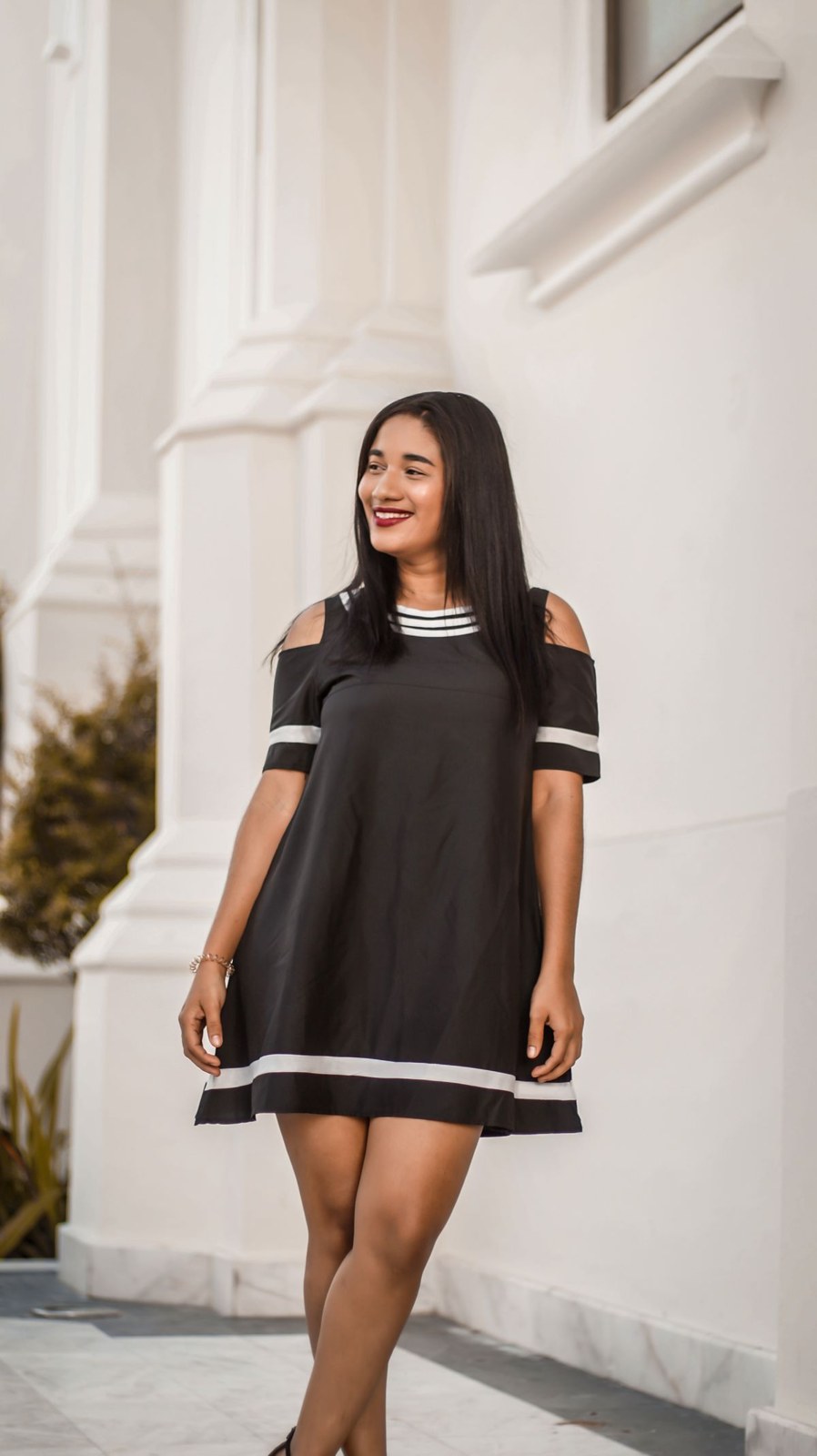 Short black dress with thin white trim at the neckline, sleeves and hem.