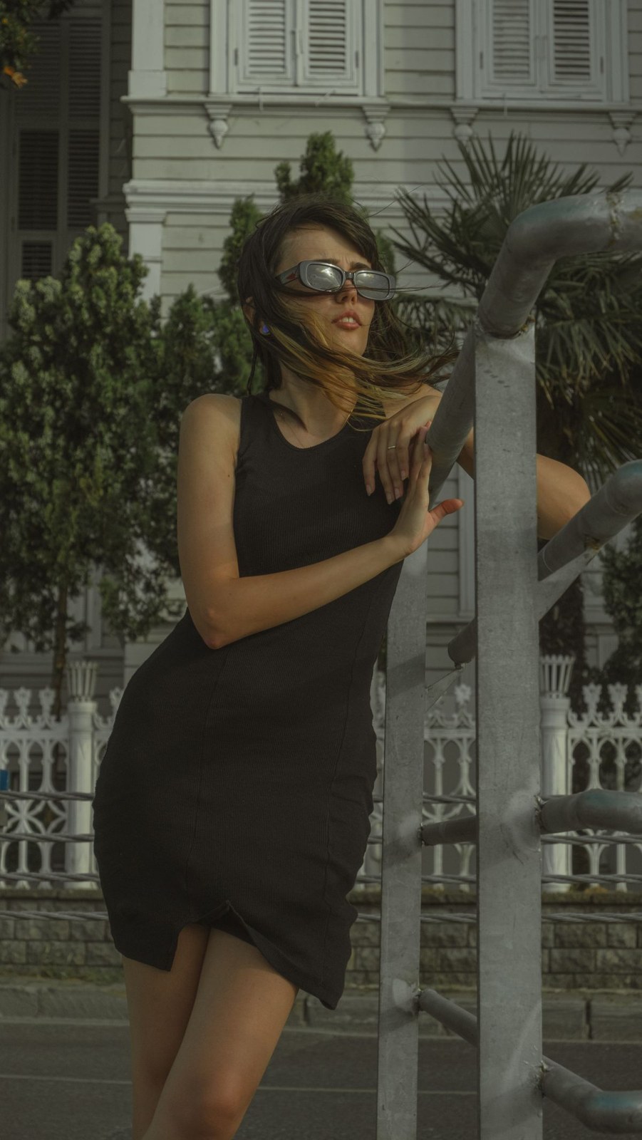Simple sleeveless short black dress and dark sunglasses.