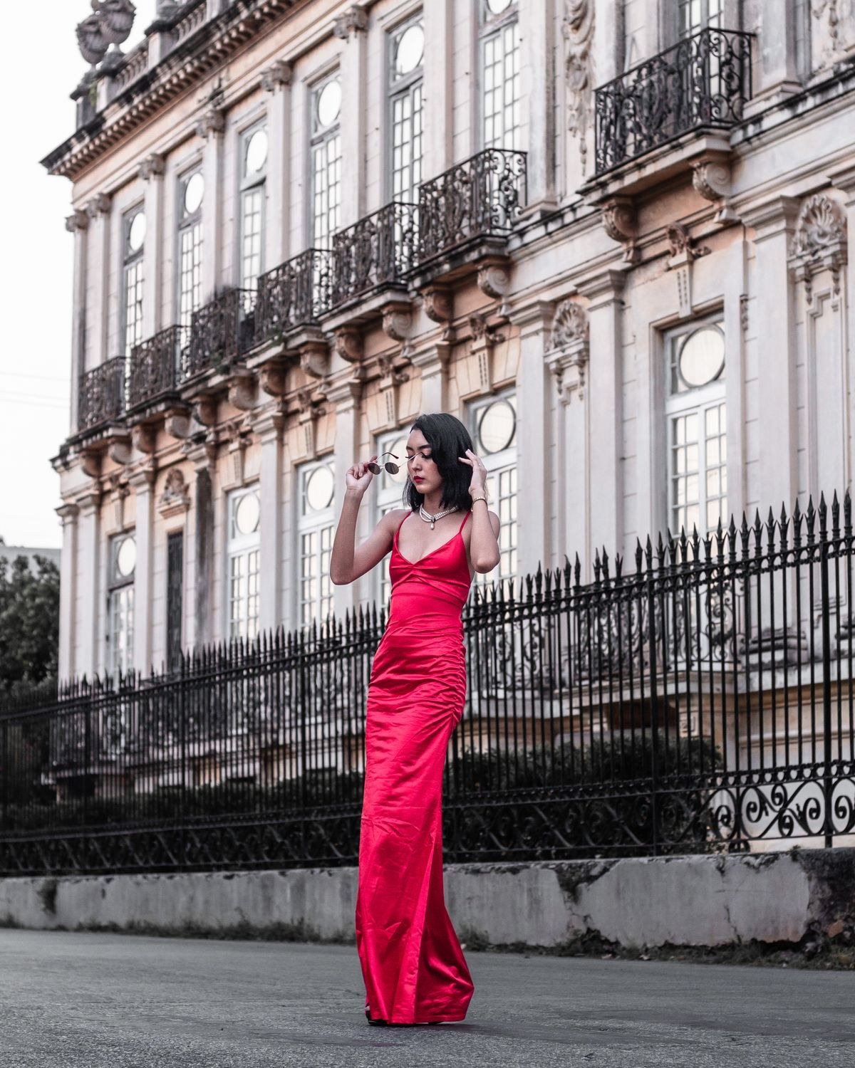 Bright pink fitted floor-length sleeveless gown on a city street.
