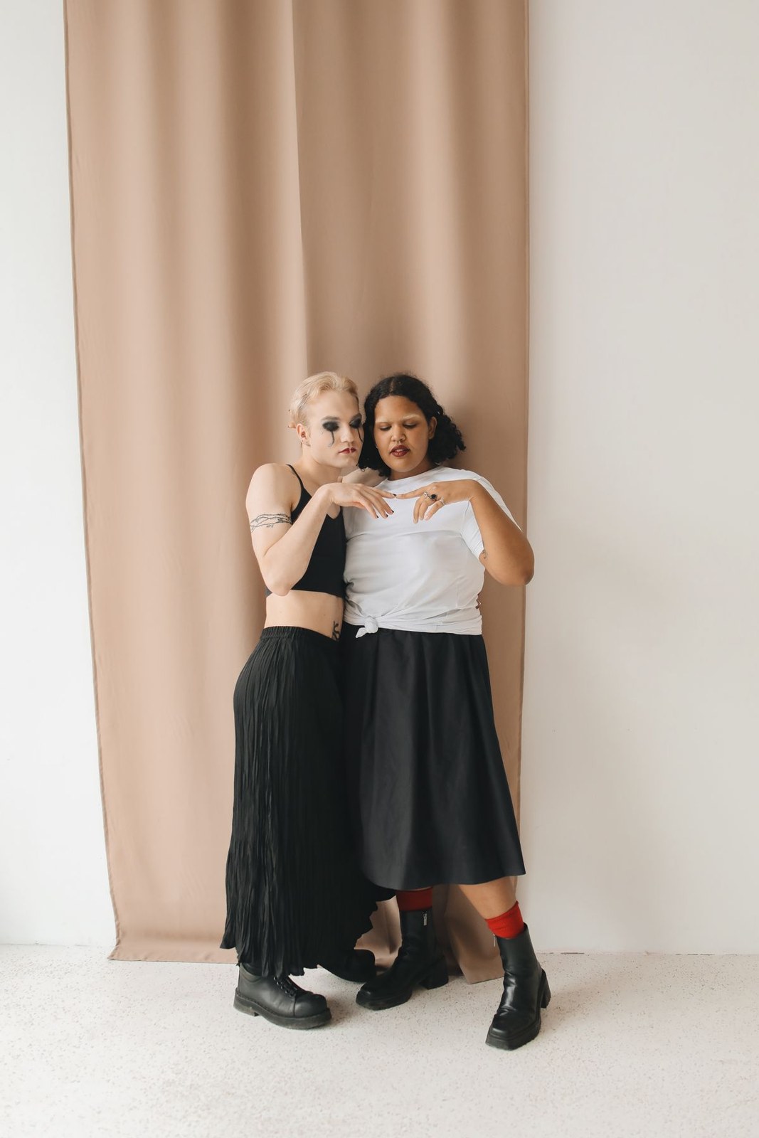 Zwei Frauen in schwarzen und weißen Oberteilen, langen dunklen Röcken und schwarzen Stiefeletten.