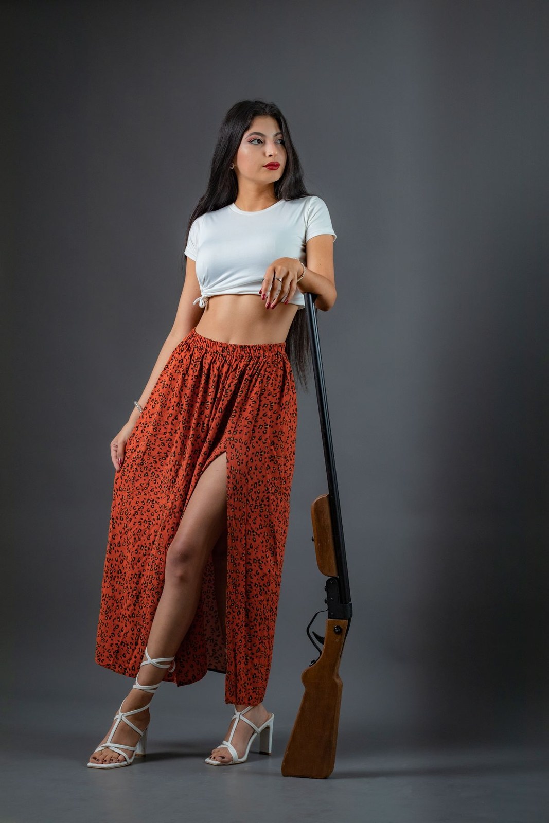 Helles Crop-T-Shirt, langer orange gemusterter Rock mit Schlitz und helle Schnürabsatzschuhe.