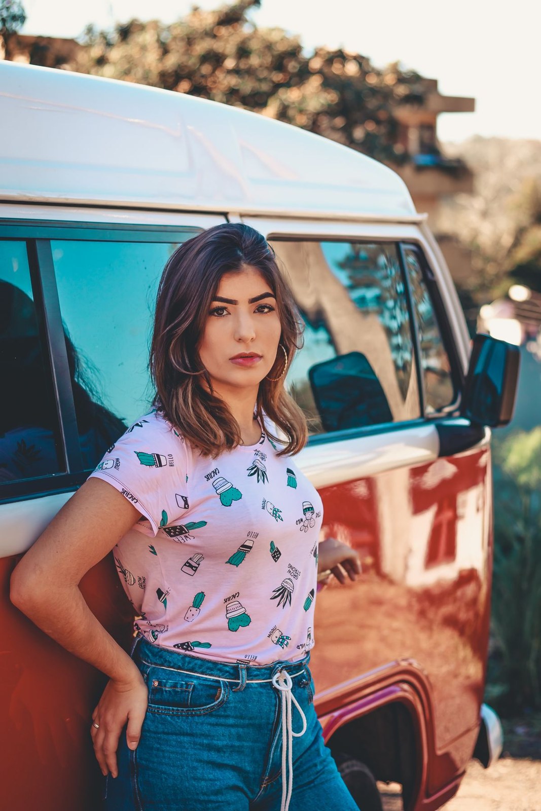 Rosa bedrucktes T-Shirt in hoch sitzender blauer Jeans mit gebundenem Taillenband.